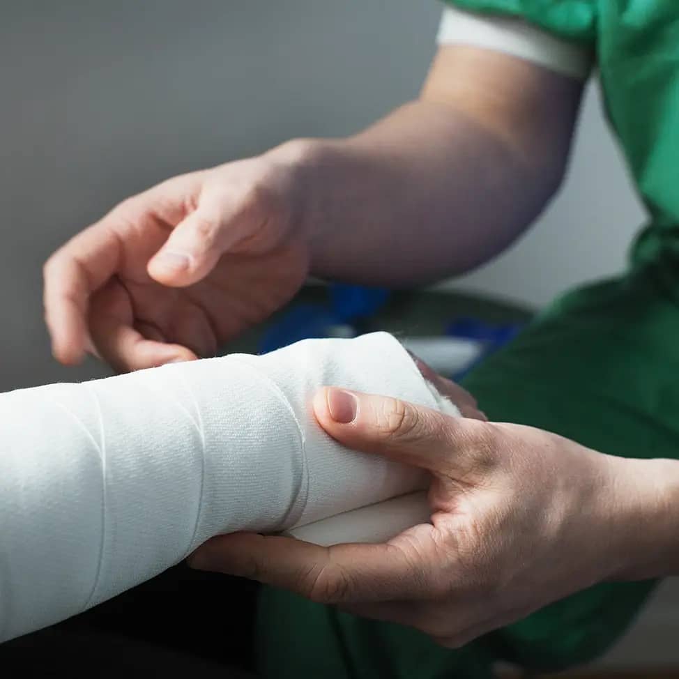 Orthopedist wrapping a cast around a patient's fractured forearm